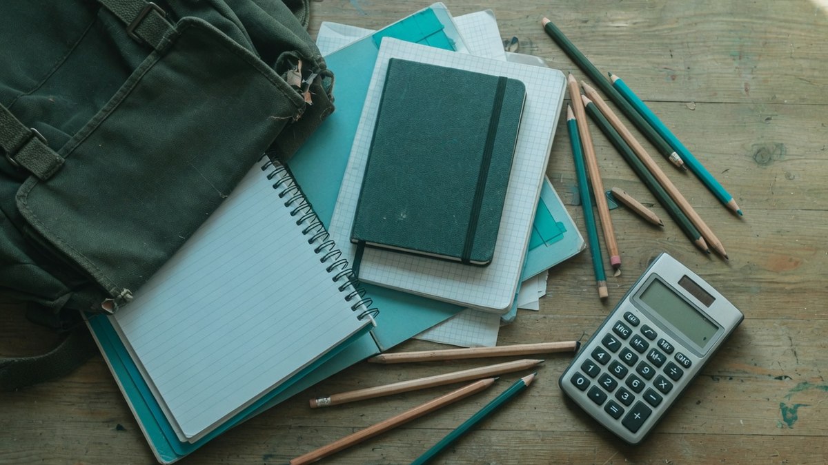 Cartable et fournitures scolaires posés sur une table en bois, vue de dessus, sans personne visible